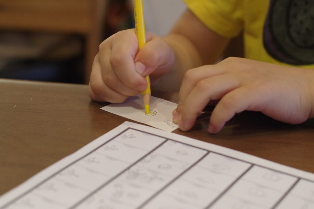 黄色い色鉛筆で絵を描く子供の手の写真。