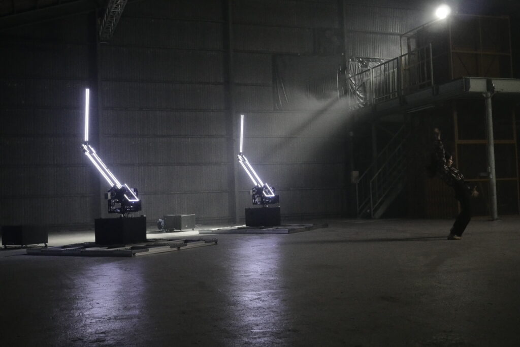 Robotic Choreographerの写真。2台のロボットアームがあり、そのロボットアームはLEDライトによって光っている。