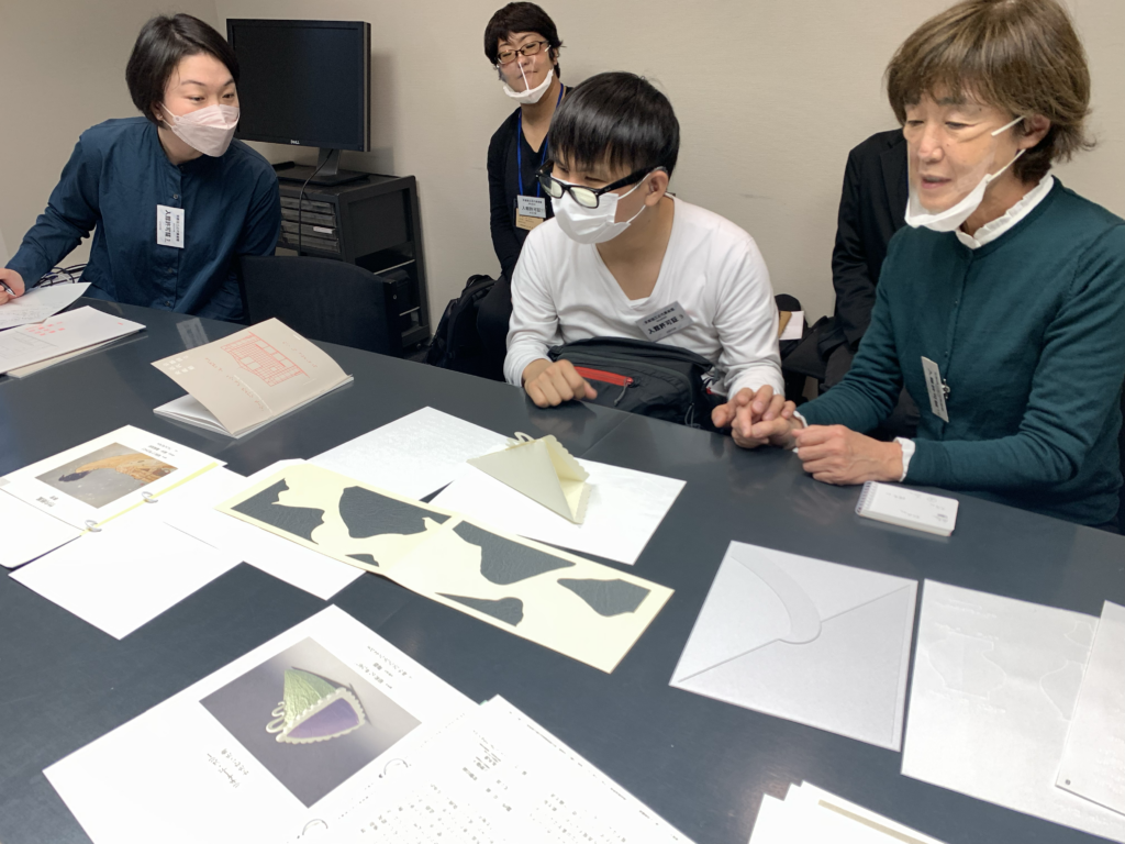 京都国立近代美術館が実施する「感覚をひらく」プロジェクトで製作された点字・拡大文字パンフレットを触る