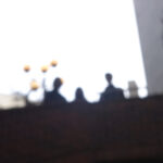 ３人の人物のシルエットが逆光で写っている、ぼやけた写真