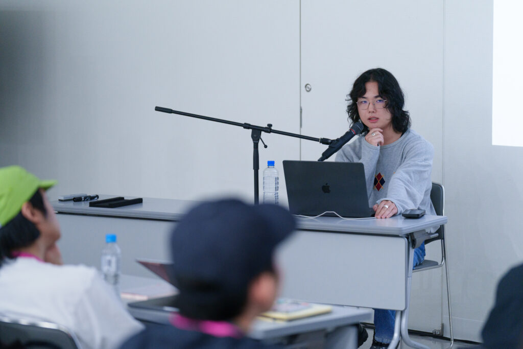 講師である岸さんがマイクの前に座り、ノートパソコンを使いながらレクチャーしている様子の写真
